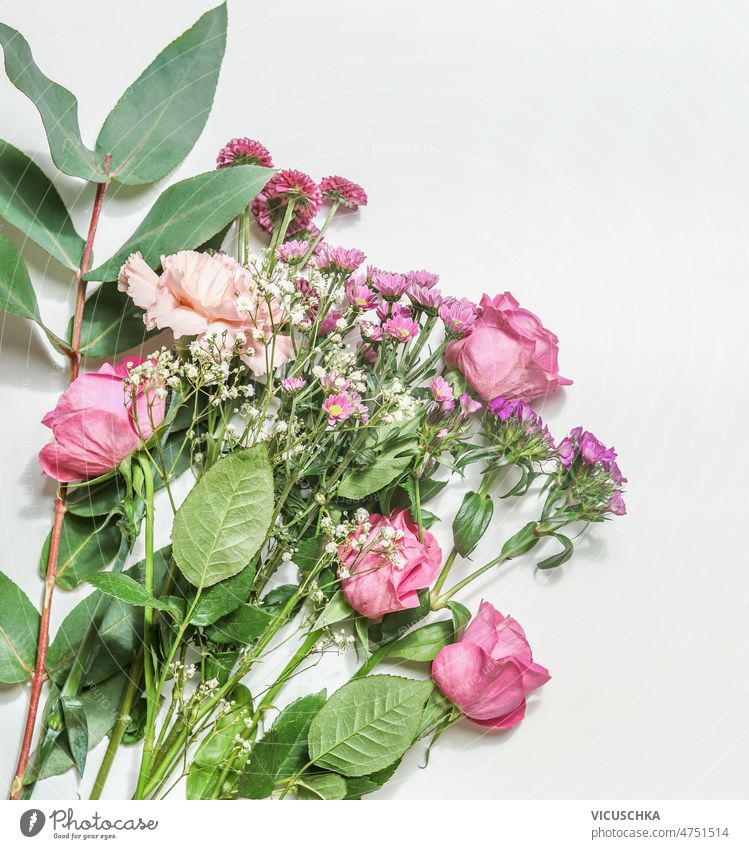 Beautiful flower bouquet with roses, pink and purple petals and green leaves at white background beautiful romantic floral setting top view beauty bloom