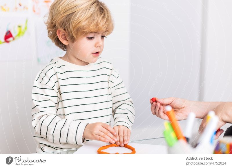 Child with sad face on paper sitting near faceless psychologist boy psychology test problem plasticine child diagnostic childhood handmade imagination visit