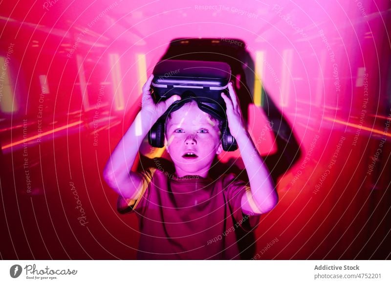 Amazed boy taking off VR helmet gamer shock vr headset take off neon illuminate videogame explore virtual reality bright amazed kid entertain device goggles