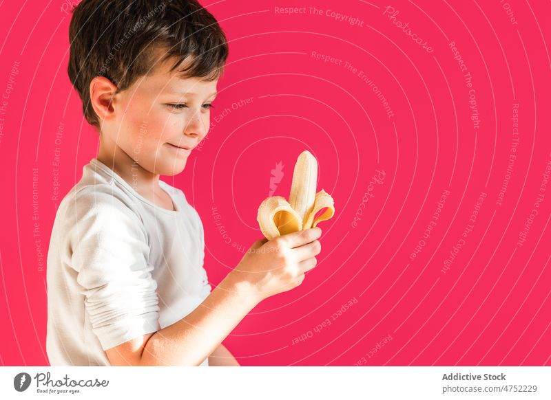 Cute boy with fresh banana in bright studio kid eat sweet fruit vivid yummy healthy food smile positive peel tasty child cute adorable nutrition childhood