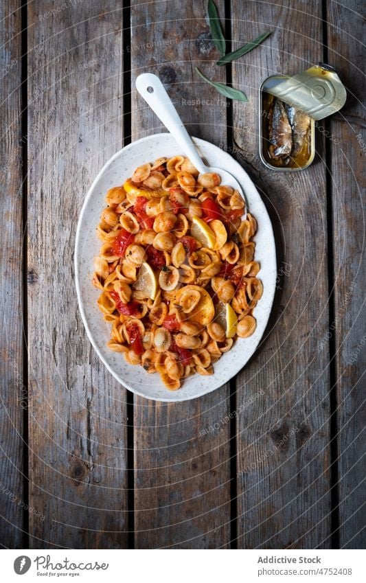 Plate of delicious Italian pasta tomato sauce sardine lemon table lunch conchiglie dish italian cuisine can plate food spoon serve portion wooden dinner