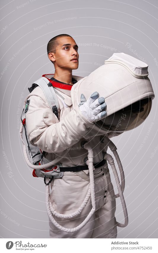 Astronaut taking off helmet of spacesuit in studio cosmonaut discovery courage looking away concept model studio shot explore universe armor take off flight