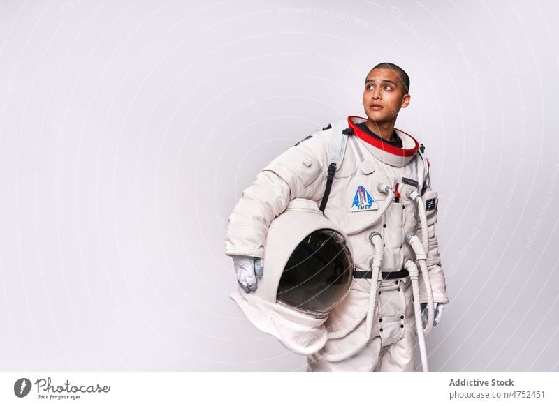 Astronaut taking off helmet of spacesuit in studio cosmonaut discovery courage looking away concept model studio shot explore universe armor take off flight