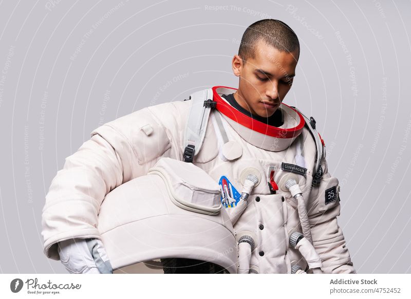 Astronaut taking off helmet of spacesuit in studio cosmonaut discovery courage looking away concept model studio shot explore universe armor take off flight