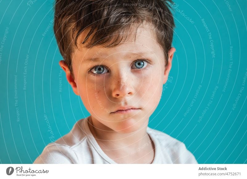 Sad boy looking down in studio kid upset childhood unhappy frustrate sad discontent displease dissatisfied mood portrait appearance light trouble disappoint