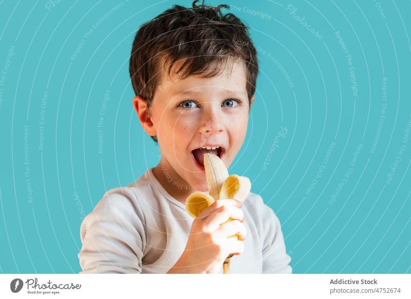 Cheerful boy eating ripe banana kid childhood fruit organic healthy food portrait natural cheerful happy positive fresh sweet glad studio optimist satisfied