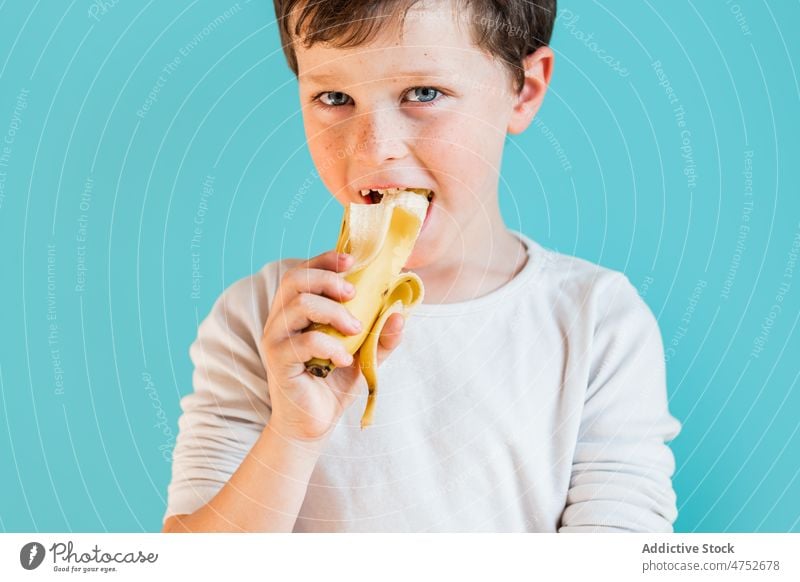 Cheerful boy with ripe banana kid childhood fruit eat organic healthy food natural cheerful happy positive fresh sweet glad studio optimist satisfied appearance