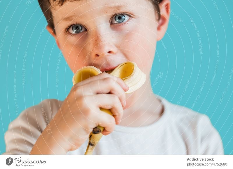 Boy eating ripe banana boy kid childhood fruit organic healthy food natural fresh sweet studio appearance vitamin cute mood hungry tasty pleasant colorful enjoy