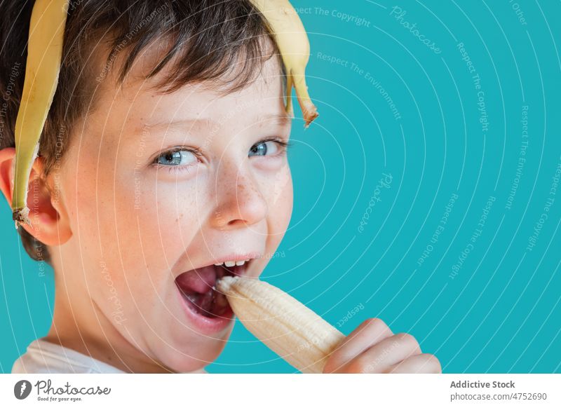 Funny boy with banana peel on head kid having fun childhood carefree playful smile portrait fruit eat cheerful ripe happy positive vitamin fresh sweet glad