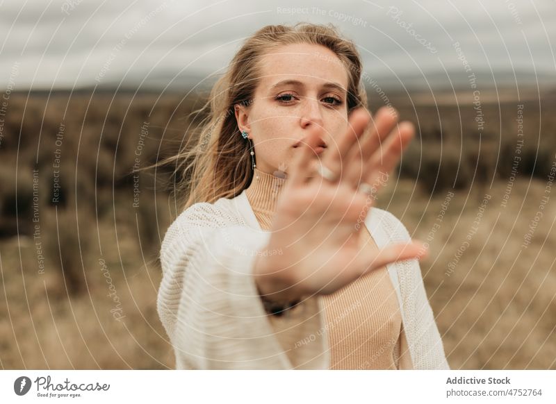 Woman showing stop gesture in field woman countryside nature refuse appearance feminine no style attractive young female environment gloomy lady rustic trip