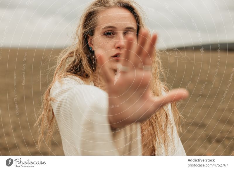 Woman showing stop gesture in field woman countryside nature refuse appearance feminine no style attractive young female environment gloomy lady rustic trip