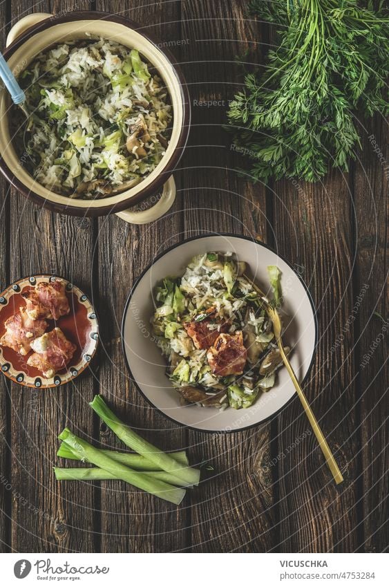 Food background with rice dish bowl, cooking pot, scallions and fried bacon food background served brown rustic wooden kitchen table delicious homemade