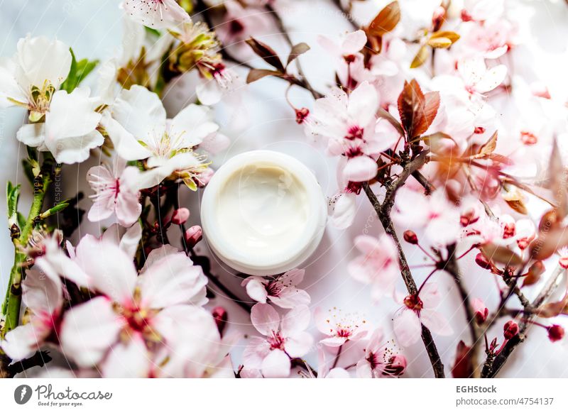 Top view of cosmetic cream with pink cherry flowers in a blue glass jar. Hygienic skincare lotion product. top view hygienic almonds spa treatment natural