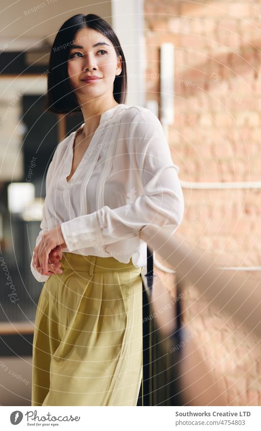 Portrait of confident mid adult Chinese businesswoman leaning on railing and looking away with a serene expression portrait chinese asian one contemplation