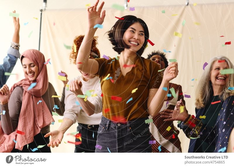 Action shot of mixed age multiethnic women celebrating International Women's Day by dancing with ticker tape action international womens day celebrate dance fun