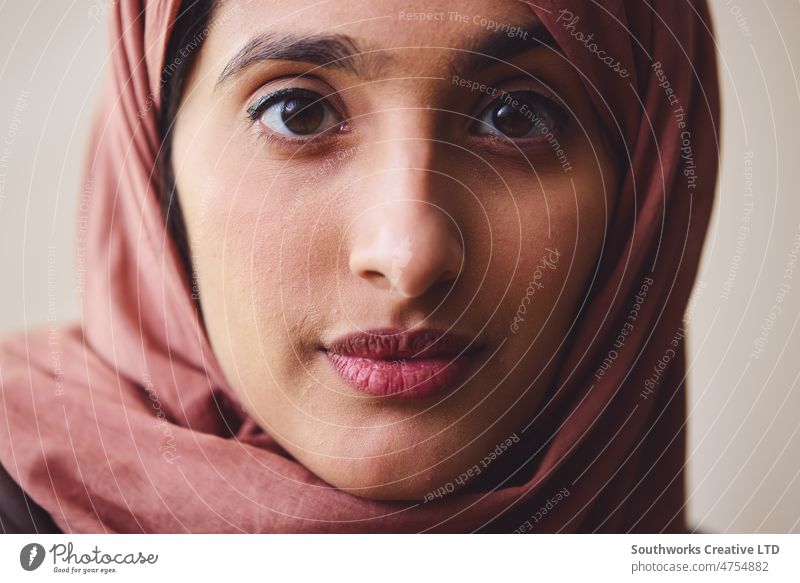 Portrait of young Muslim woman wearing hijab looking towards camera with pensive expression portrait muslim middle eastern one pride confident