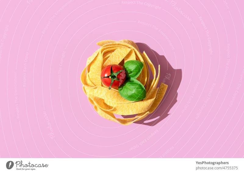 Pasta nest uncooked, top view on a pink background. above alfredo arrangement basil bright carbs cherry close-up color cuisine dry fettuccine food gourmet green