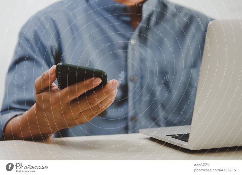 man using mobile smart phone and computer laptop searching internet, sending sms, using text messenger or online banking. business typing technology businessman