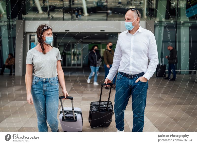 Travellers in protective masks chatting while leaving the airport with their luggage travel pandemic woman talk boy friends people couple traveller destination