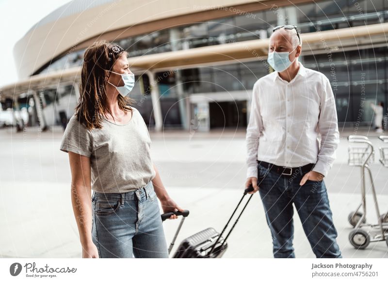 Travellers in protective masks chatting while leaving the airport with their luggage travel pandemic woman talk boy friends people couple traveller destination