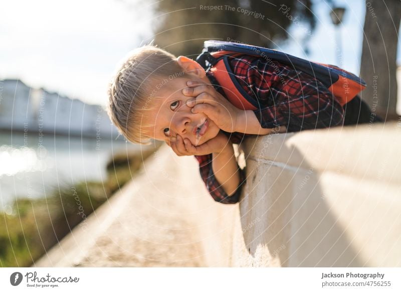 Cute small boy doing faces in his free time by the river kid nature funny do faces play copy space childhood relax backpack vacation outdoors portugal tavira