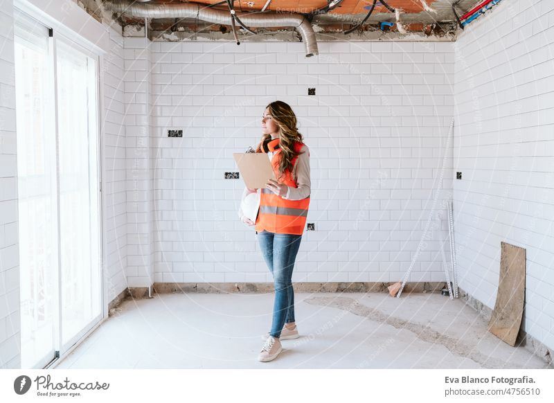 inspector or architect professional woman checking kitchen at construction site. Home improvement home laptop unrecognizable mobile phone blueprints workspace