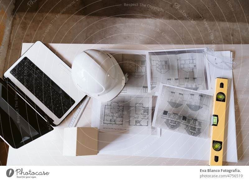 blueprints, protective helmet, laptop,house model and tools on architect workspace.Construction site model house nobody level daytime real state work place home