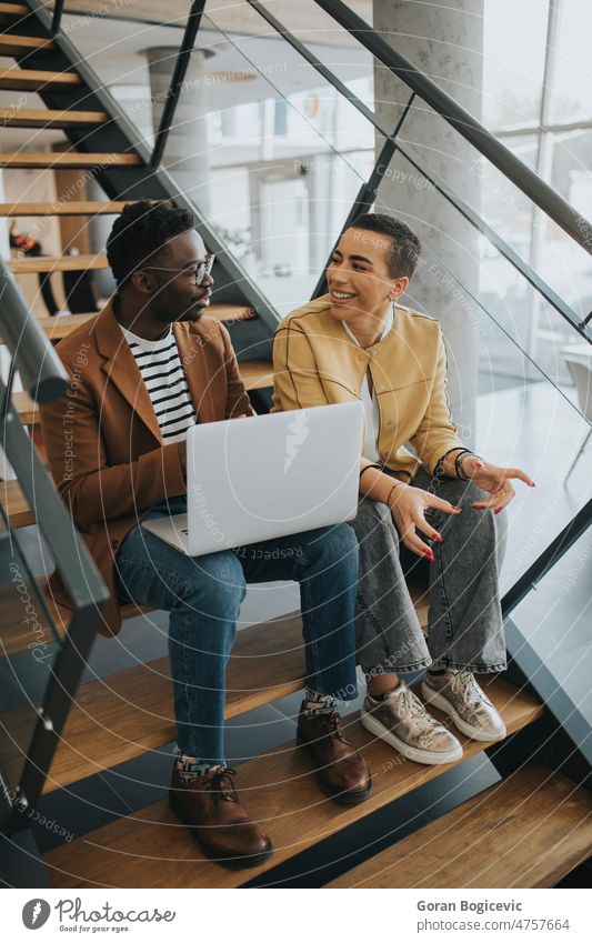 Young African American business man and short hair woman working on laptop while sitting at office stairs person adult young african american black