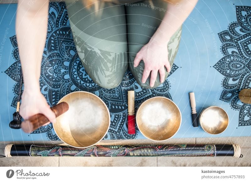 Yoga concept, meditation and sound therapy. Beautiful young caucasian woman surrounded by copper tibetan singing bowls and instruments buddhism meditating