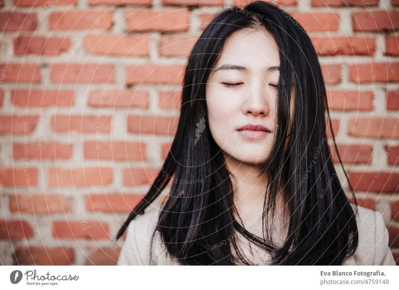 relaxed beautiful chinese business woman standing over bricks wall background with eyes closed asian laptop technology cafe coffee cafeteria tablet mobile phone