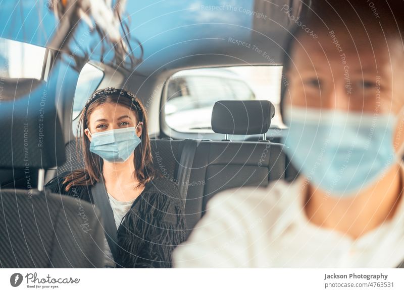 A woman wearing a protective mask on the back seat of a taxi car tourist passenger driver uber client reflection private smile happy discover traveler commuter