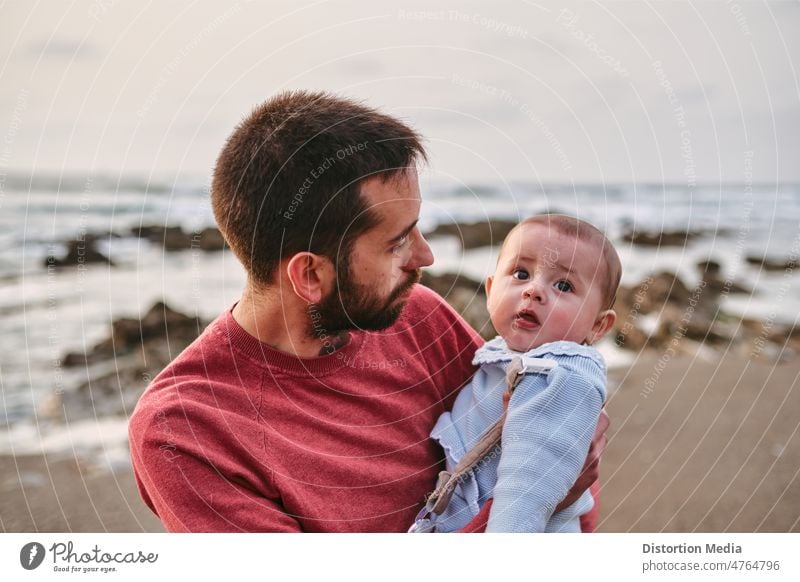 Young single father hugging his baby son on the beach travel with baby childhood sunlight seaside looking infant boy caucasian dad family happiness happy kid