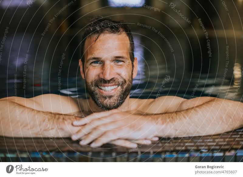 Portrait of smiling young man relaxing by the swimming pool edge handsome man handsome young man poolside male summer swimwear vacation swimmer water sport