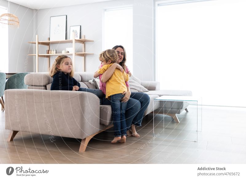 Mother hugging son near daughter mother children sibling pastime spend time living room love childhood cuddle caress embrace motherhood bonding together