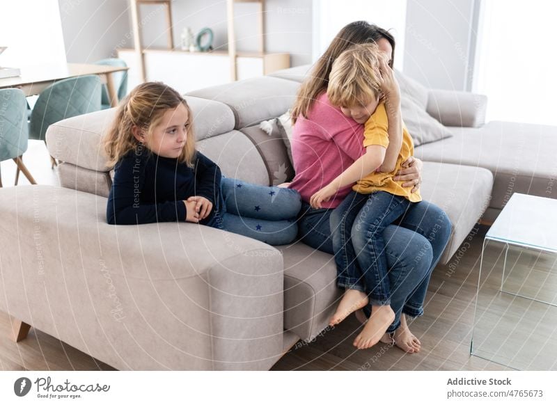 Mother hugging son near daughter mother children sibling pastime spend time living room love childhood cuddle caress embrace motherhood bonding together