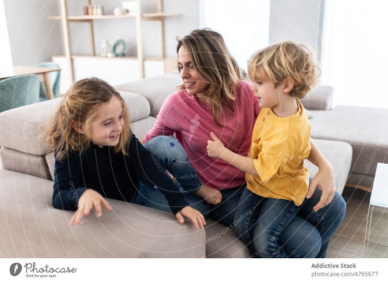 Mother hugging son near daughter mother children sibling pastime spend time living room love childhood cuddle caress embrace motherhood bonding together