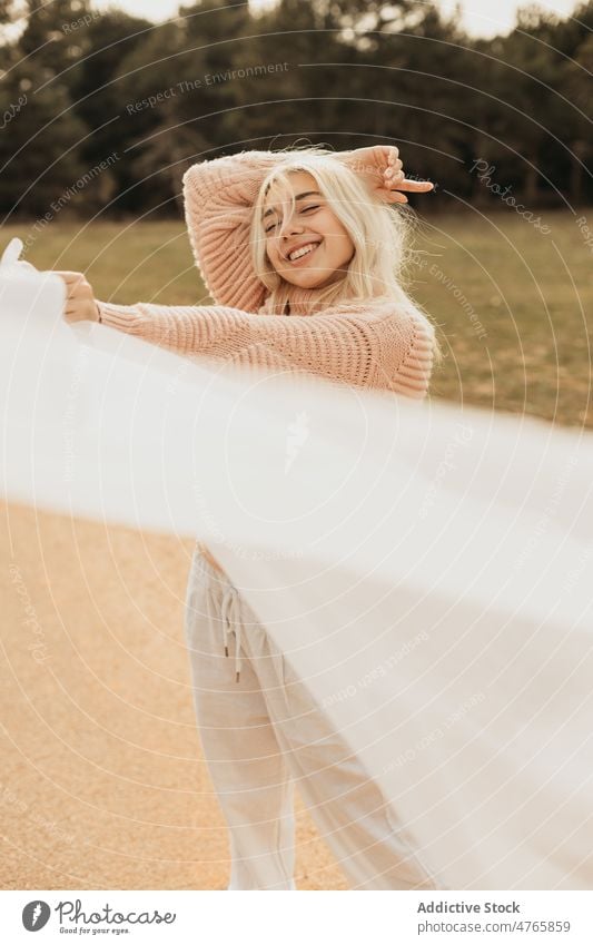 Fair haired smiling female with white sheet standing on road woman asphalt roadway style enjoy cloth freedom portrait carefree forest nature tree woods woodland