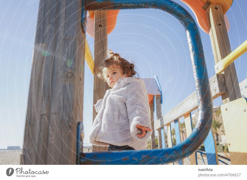 Little girl enjoying a winter sunny day at the beach playground toddler happy curious playful explore family adorable lovely childcare childhood emotion mood