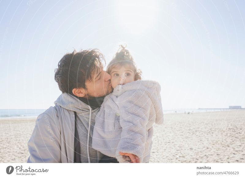 Single dad carring her baby in a sunny day single parent family affection toddler hug carry girl daughter beach winter sunshine love backlight new modern