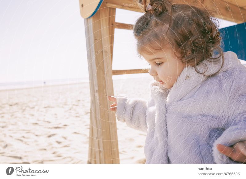 Little girl enjoying a winter sunny day at the beach playground toddler happy curious playful explore family adorable lovely childcare childhood emotion mood