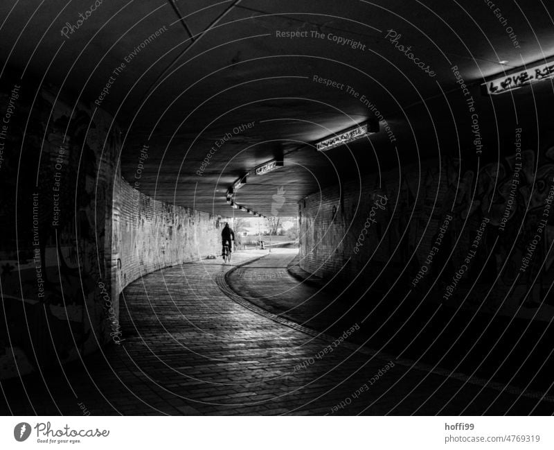 Cyclist in underpass with light at the end of the tunnel Light at the end of the tunnel Underpass Cycling Tunnel cycle path Lanes & trails Corridor Dark Shadow