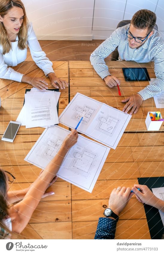 Top view of architects in a work meeting looking at construction drawings teamwork businesspeople office cooperation top view pointing brainstorming