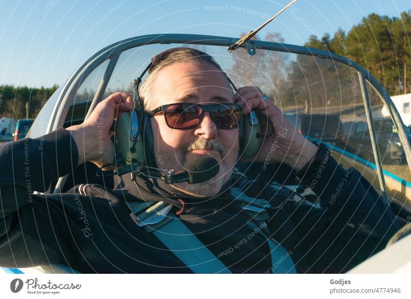 Portrait of a man putting on a headset on a plane Man portrait Airplane Aviation Headset Facial hair Face Adults Human being Eyeglasses Colour photo Sunglasses