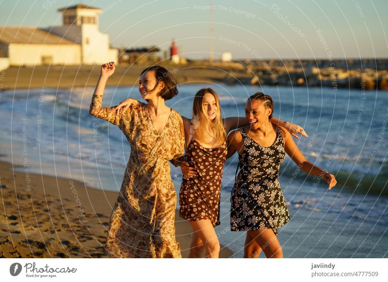 Happy diverse girlfriends walking on sandy beach women carefree sea hug enjoy cheerful sundown freedom female together stroll embrace seashore best friend