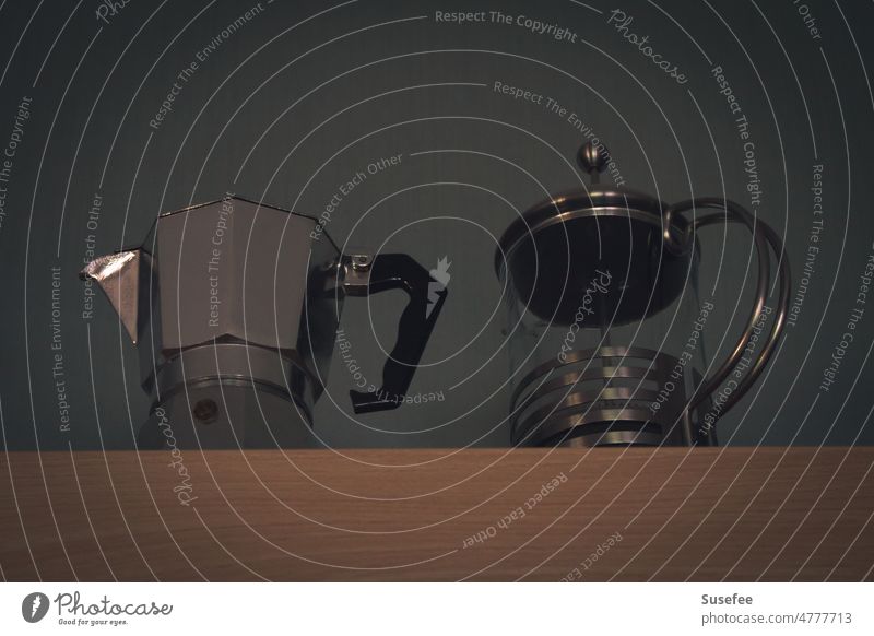 Two different coffee makers. An espresso maker and a French press in stainless steel and glass top on a cabinet photographed from below. Coffee Espresso Hot