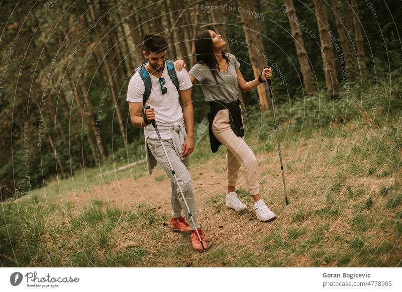 Couple of hikers with backpacks walk through the forest nature hiking activity trekking young woman freedom leaves girl lifestyle young man female adventure