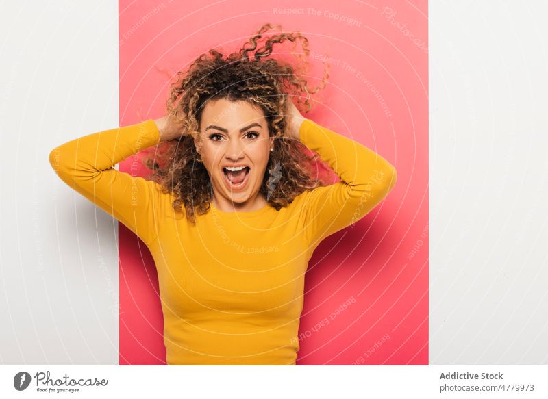 Smiling young woman ruffling hair with hands curly hair happy colorful cheerful smile positive bright casual optimist style joy model glad outfit appearance