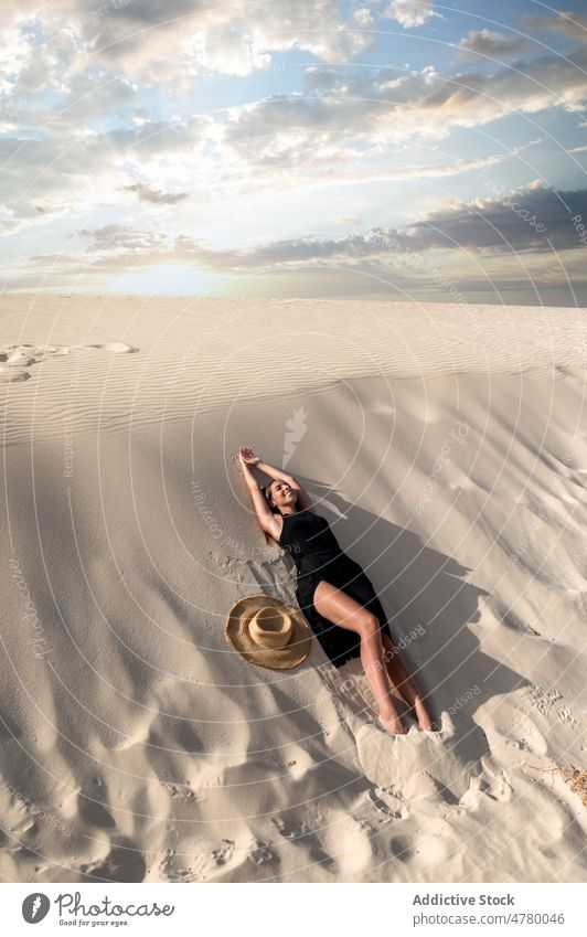 Traveler lying down in desert at sunset tourist stroll hill sky explore wanderlust nature woman landscape traveler cloudy vacation trip island spain corralejo