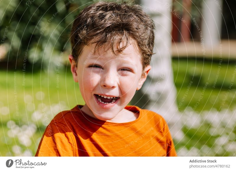 Content boy standing on street portrait kid park appearance childhood style city leisure pastime casual cute dark hair adorable content glad summertime smile