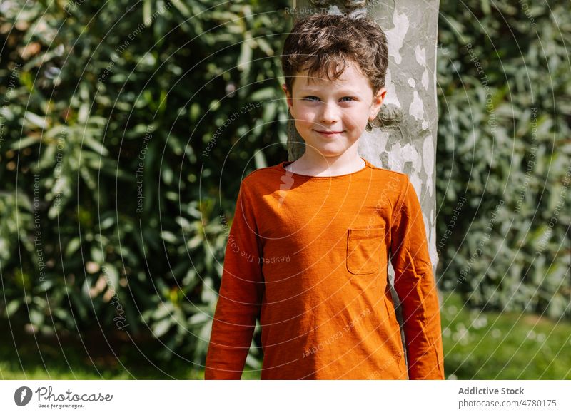 Content boy standing on street kid appearance childhood portrait style city leisure pastime casual cute dark hair adorable content glad summertime smile happy